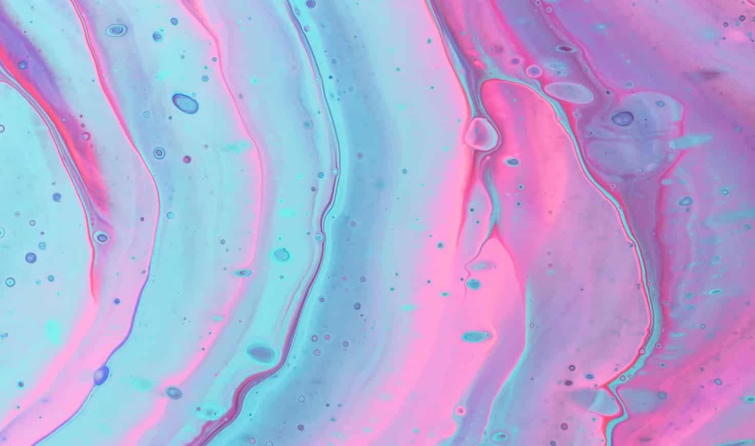 Ondulations irisées d'un liquide bleu vif et rose.